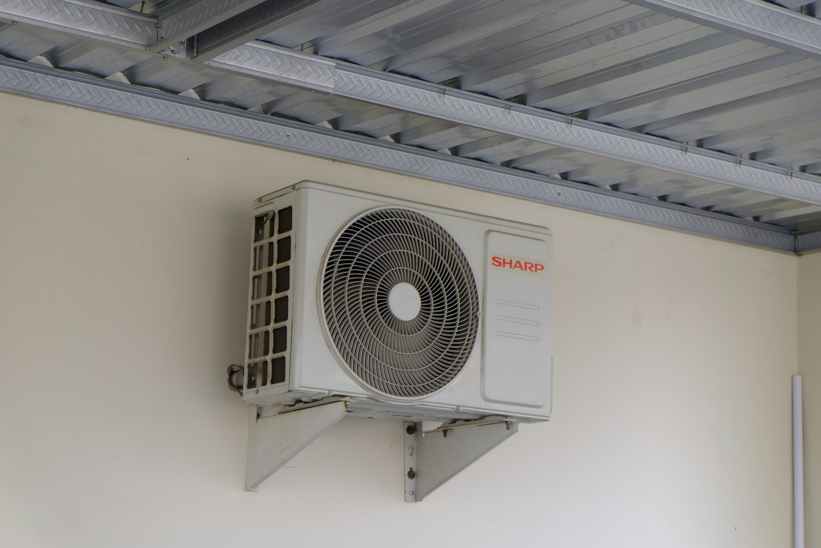 An outdoor wall-mounted air-conditioning unit beneath a metal awning